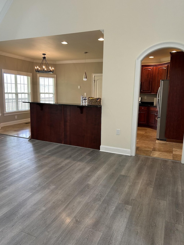 interior space featuring crown molding, a chandelier, wood finished floors, and baseboards