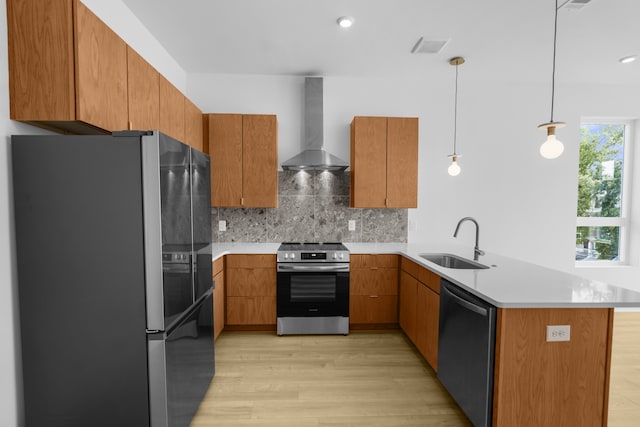 kitchen featuring wall chimney exhaust hood, appliances with stainless steel finishes, hanging light fixtures, kitchen peninsula, and sink