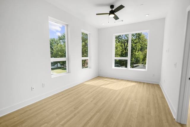 empty room featuring a healthy amount of sunlight, ceiling fan, and light hardwood / wood-style floors