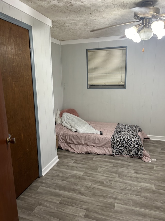 bedroom with dark wood-type flooring, a textured ceiling, and ceiling fan