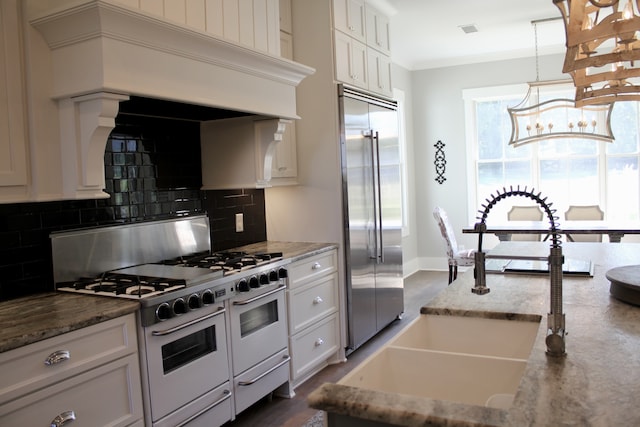 kitchen featuring white cabinets, backsplash, high end appliances, dark wood-type flooring, and pendant lighting