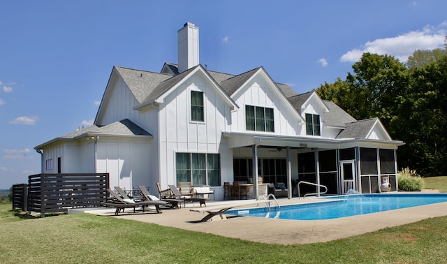 back of property with a sunroom, a lawn, and a patio area