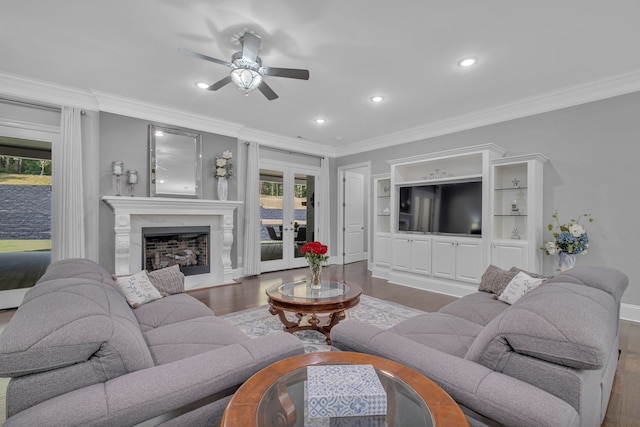 living room featuring ornamental molding, ceiling fan, a high end fireplace, and hardwood / wood-style floors