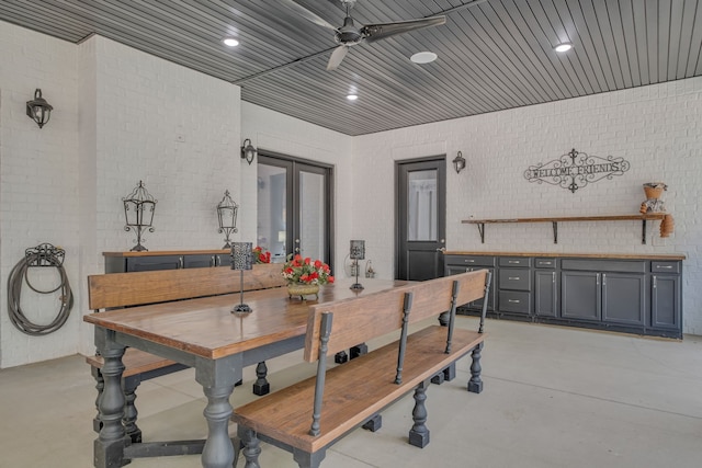 dining room with french doors, ceiling fan, and brick wall