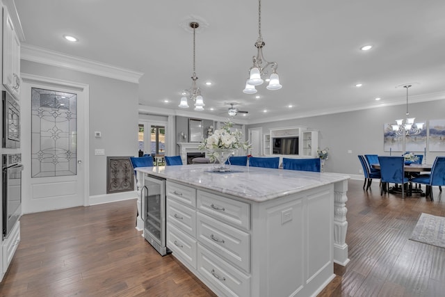 kitchen with beverage cooler, white cabinets, a kitchen island, and dark hardwood / wood-style flooring