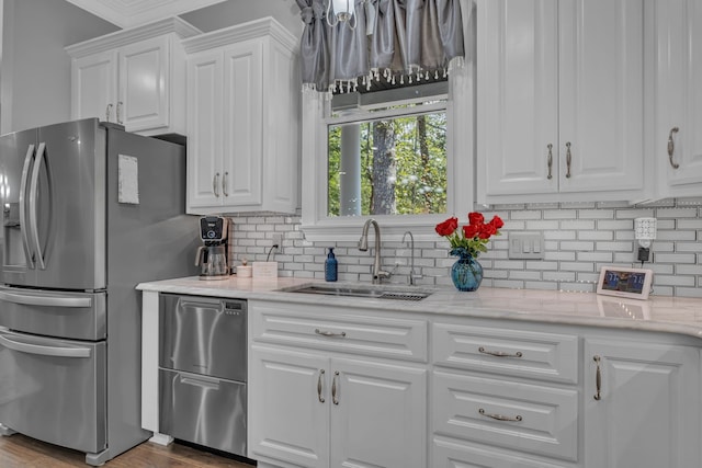 kitchen featuring backsplash, wood-type flooring, appliances with stainless steel finishes, sink, and white cabinets