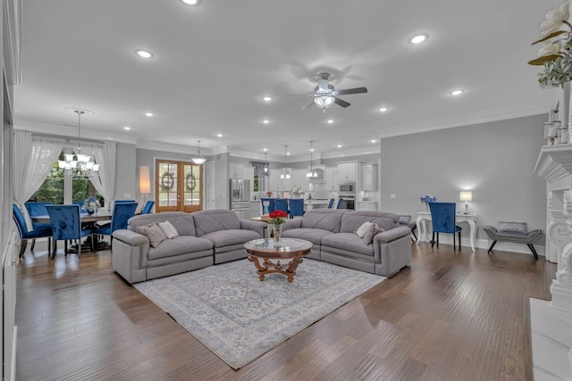 living room with ceiling fan with notable chandelier, dark hardwood / wood-style flooring, and ornamental molding