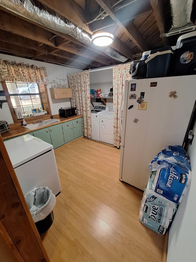 450 Pinson Ln, Big Sandy, TN 38221 - kitchen with light wood finished floors, green cabinetry, freestanding refrigerator, black microwave, and independent washer and dryer