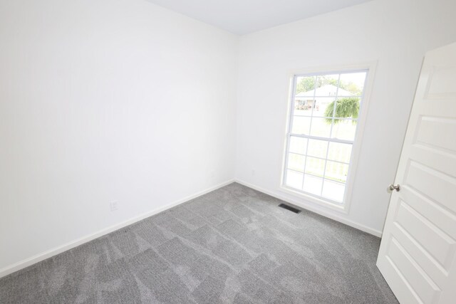 carpeted spare room with visible vents and baseboards