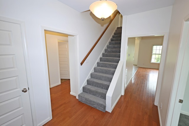 staircase with baseboards and wood finished floors