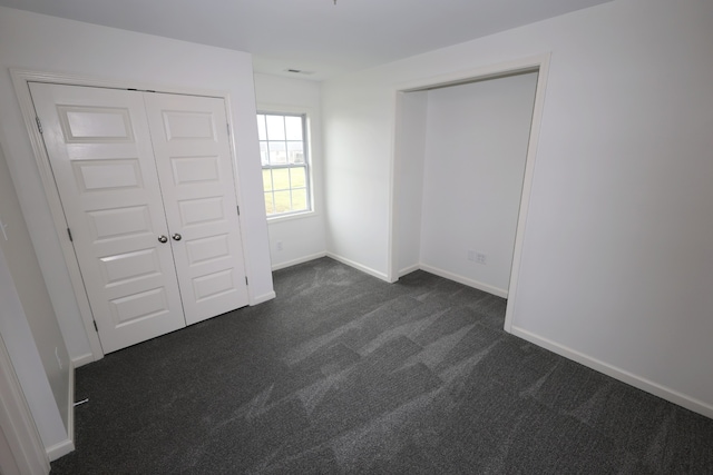 unfurnished bedroom featuring dark carpet and a closet