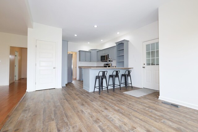 kitchen featuring kitchen peninsula, light hardwood / wood-style flooring, a kitchen breakfast bar, and appliances with stainless steel finishes