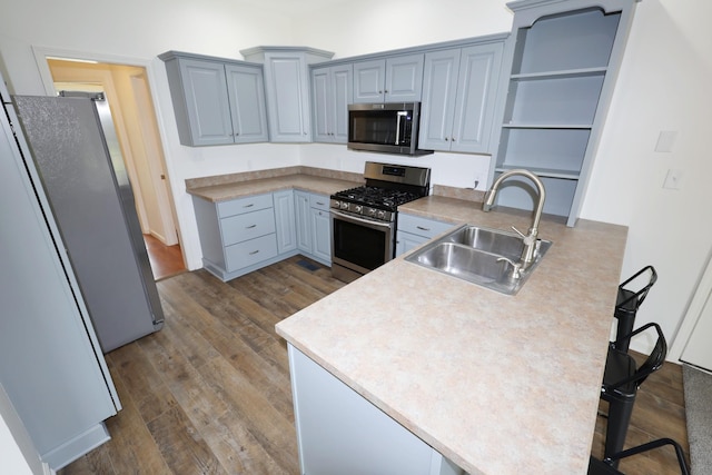 kitchen featuring stainless steel appliances, dark wood-type flooring, a peninsula, a sink, and open shelves