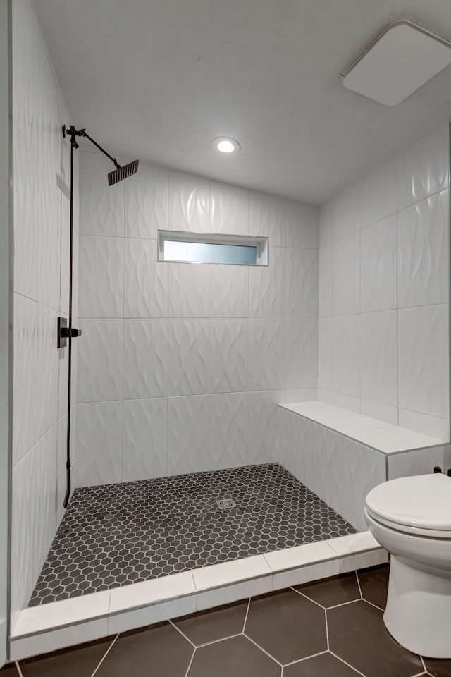 bathroom featuring tile walls, toilet, tiled shower, and tile patterned flooring