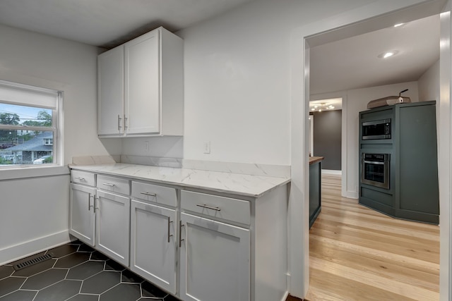 kitchen featuring light stone counters, hardwood / wood-style flooring, stainless steel appliances, and white cabinetry