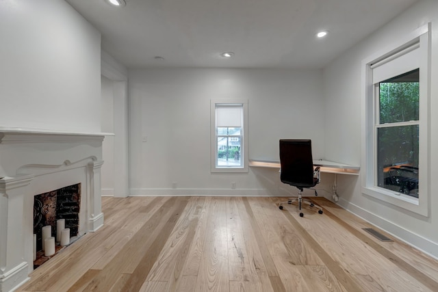 unfurnished office featuring a fireplace and light hardwood / wood-style flooring