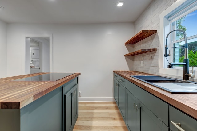 kitchen with light hardwood / wood-style flooring, black electric cooktop, sink, and butcher block counters