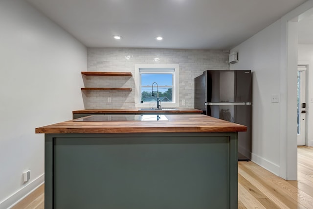 kitchen featuring butcher block countertops, black appliances, light hardwood / wood-style floors, and sink