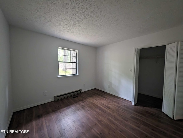 unfurnished bedroom featuring a textured ceiling, dark hardwood / wood-style flooring, baseboard heating, and a closet