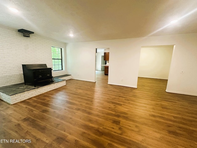 unfurnished living room featuring a textured ceiling, a wood stove, and dark hardwood / wood-style floors