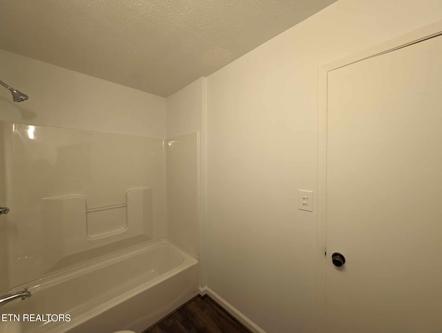 bathroom featuring a textured ceiling, shower / tub combination, and hardwood / wood-style flooring