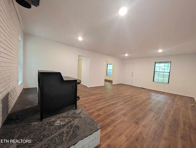 living room with dark wood-type flooring, a textured ceiling, and brick wall