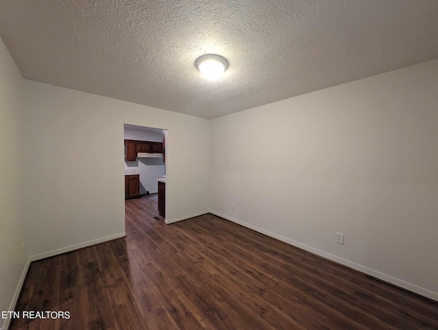 unfurnished room with a textured ceiling and dark wood-type flooring