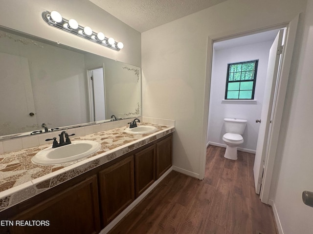 bathroom featuring a textured ceiling, vanity, toilet, and hardwood / wood-style flooring