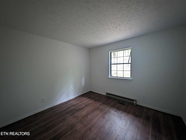 spare room with dark wood-type flooring, a textured ceiling, and baseboard heating