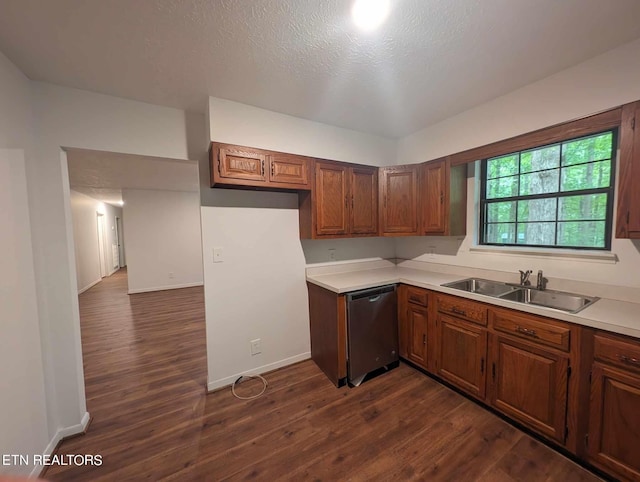 kitchen featuring a textured ceiling, stainless steel dishwasher, sink, and dark wood-type flooring