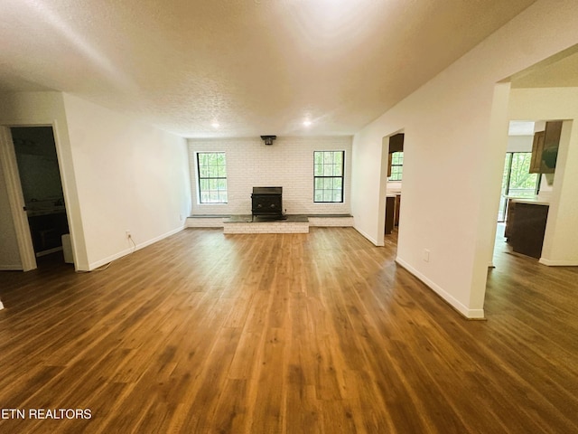 unfurnished living room with dark hardwood / wood-style flooring, a textured ceiling, and plenty of natural light