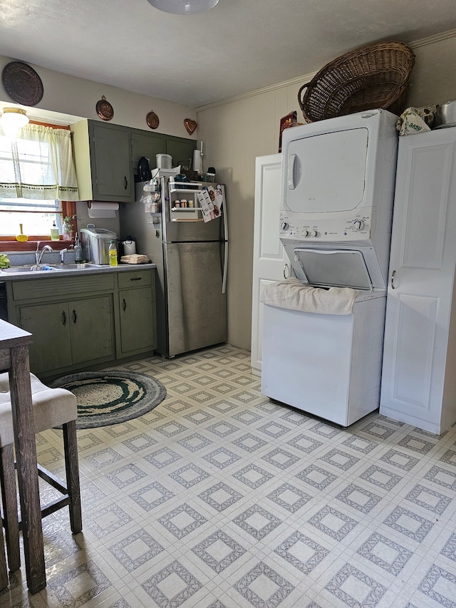 interior space with stainless steel fridge, sink, green cabinetry, and stacked washer and dryer