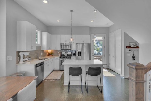 kitchen featuring pendant lighting, white cabinetry, stainless steel appliances, a kitchen island, and sink