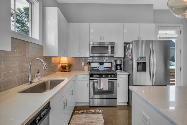 kitchen featuring backsplash, light stone counters, sink, appliances with stainless steel finishes, and white cabinets