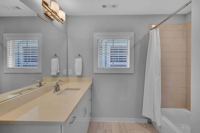 bathroom with a wealth of natural light, vanity, hardwood / wood-style flooring, and shower / bathtub combination with curtain