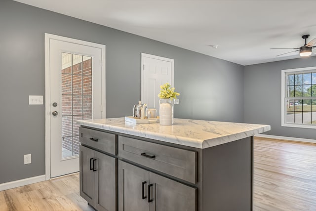 kitchen with light hardwood / wood-style flooring, a kitchen island, and ceiling fan