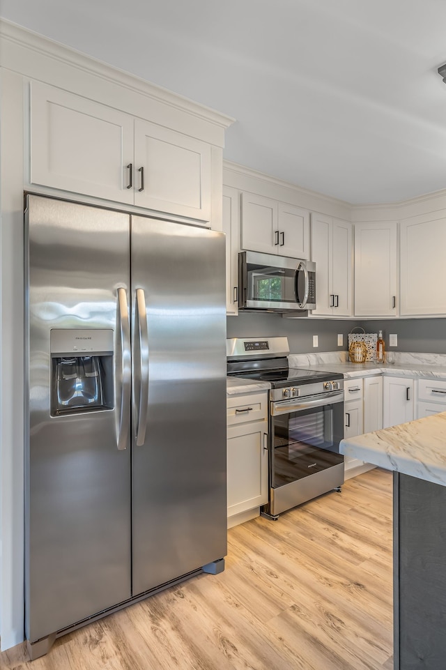 kitchen featuring white cabinets, appliances with stainless steel finishes, light stone countertops, and light hardwood / wood-style flooring