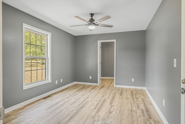 empty room featuring a healthy amount of sunlight, ceiling fan, and light hardwood / wood-style flooring