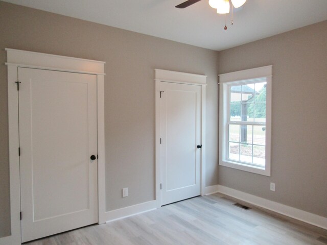 unfurnished bedroom with light wood-type flooring, multiple windows, and ceiling fan