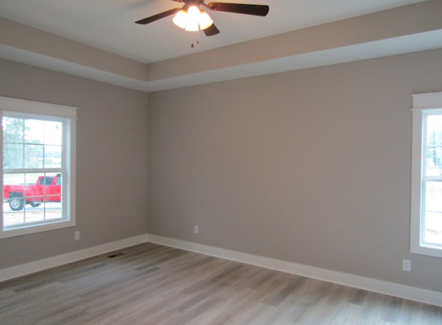 empty room featuring plenty of natural light, ceiling fan, and light wood-type flooring