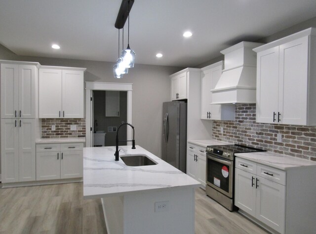 kitchen featuring white cabinets, premium range hood, stainless steel appliances, and sink