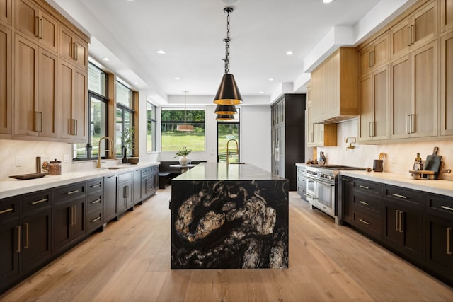 kitchen featuring light wood-type flooring, double oven range, a spacious island, and sink