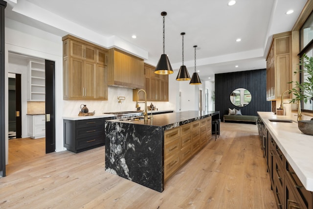 kitchen featuring a spacious island, sink, pendant lighting, and light wood-type flooring