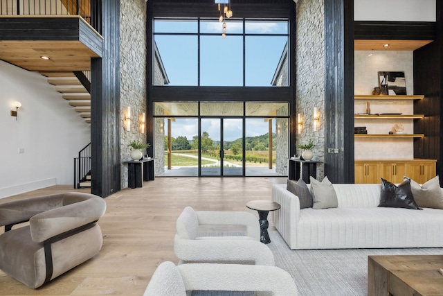 living room with plenty of natural light, a towering ceiling, and light wood-type flooring