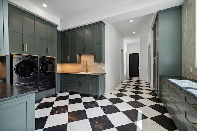 kitchen with decorative backsplash, washer and clothes dryer, green cabinets, and sink