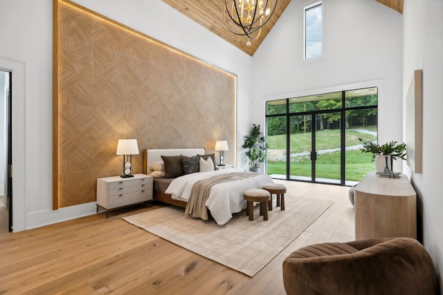 bedroom featuring light hardwood / wood-style floors, access to exterior, high vaulted ceiling, and a chandelier