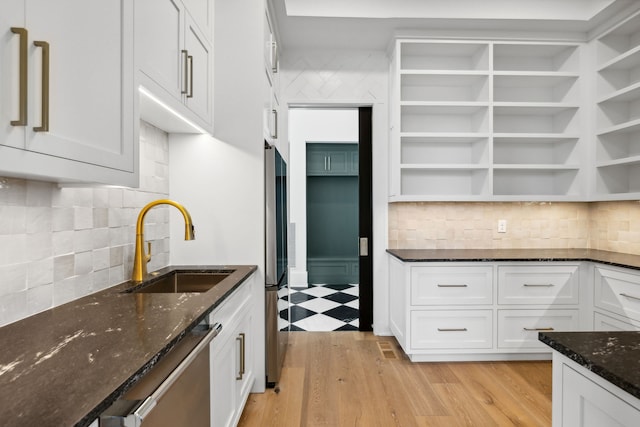 kitchen with decorative backsplash, appliances with stainless steel finishes, sink, dark stone countertops, and white cabinetry