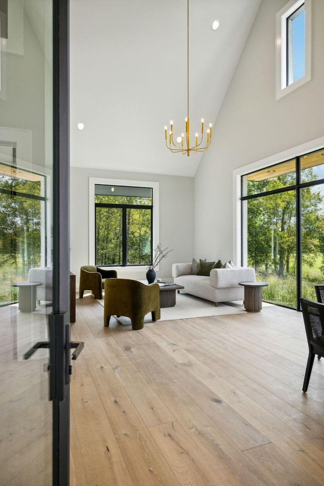 living room featuring a wealth of natural light, high vaulted ceiling, and a notable chandelier