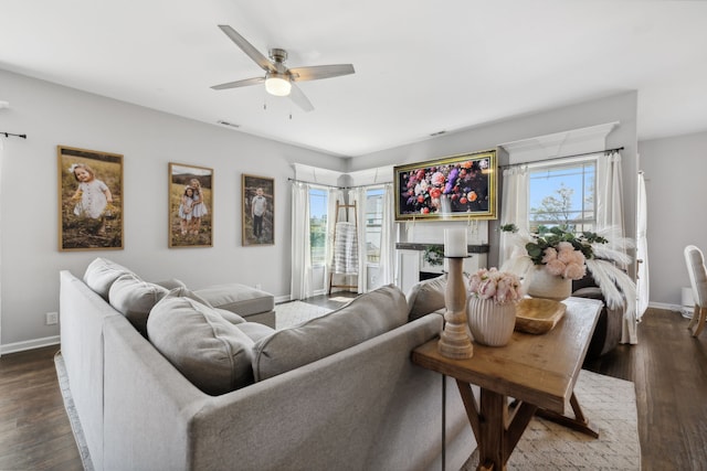 living room featuring a healthy amount of sunlight, ceiling fan, and dark wood-type flooring