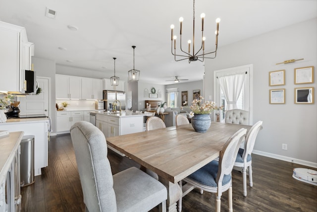 dining space with dark hardwood / wood-style floors, ceiling fan with notable chandelier, and sink